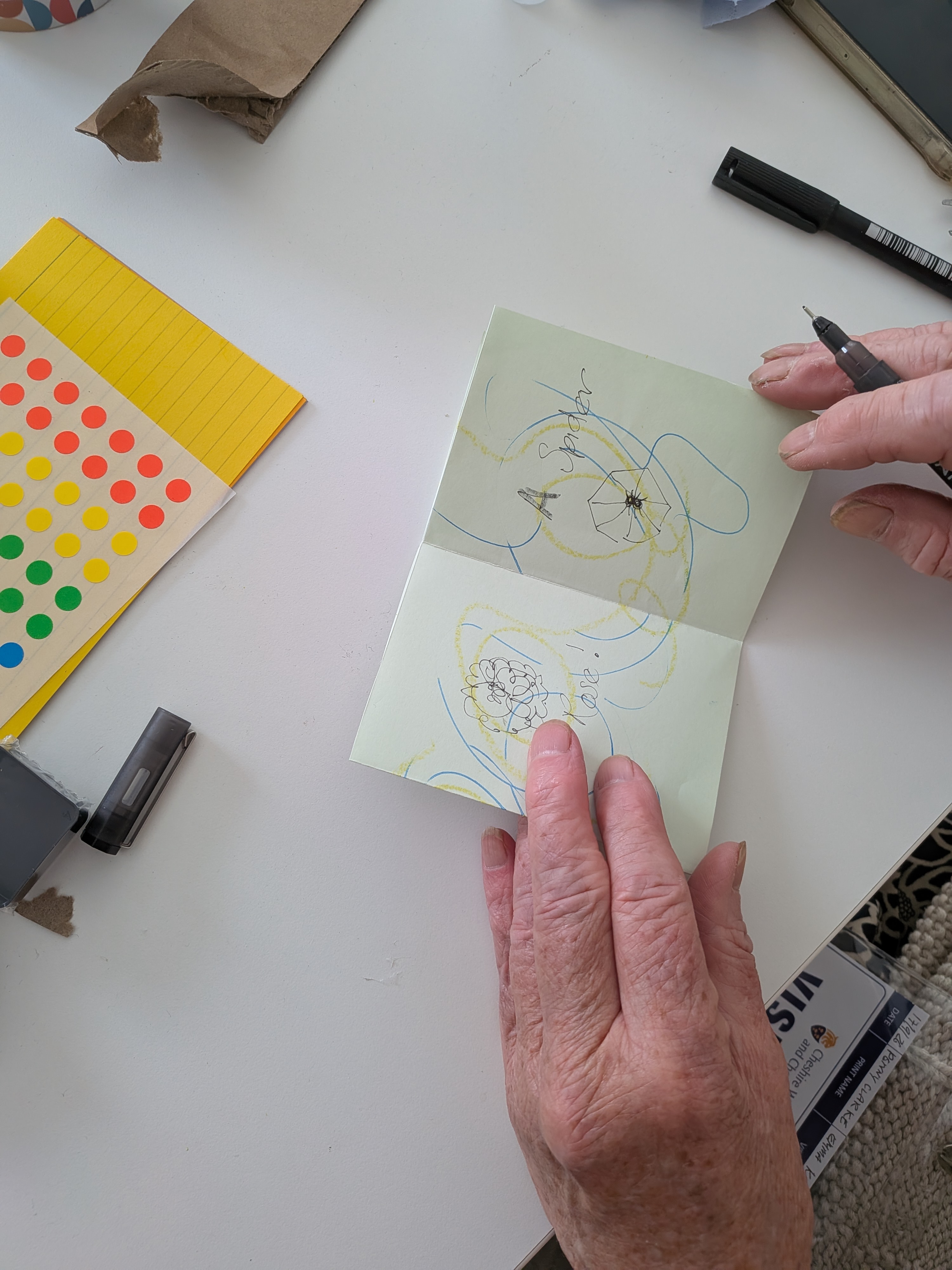 Hands drawing and writing on folded paper